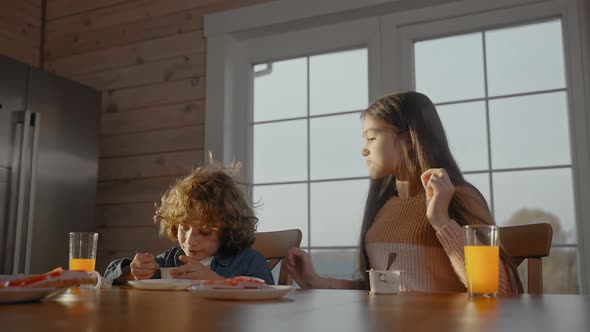 Man Hugs His Children Having Fun and Eating at Breakfast on a Sunny Day