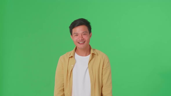 Smiling Asian Man Positively Shaking His Head At The Camera In The Green Screen Studio