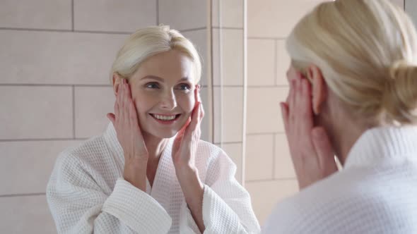 Happy Smiling Mid Age Blond Woman Standing Looking at Mirror