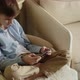 Boy Sits in a Chair Holds a Phone in His Hand and Plays on the Phone - VideoHive Item for Sale