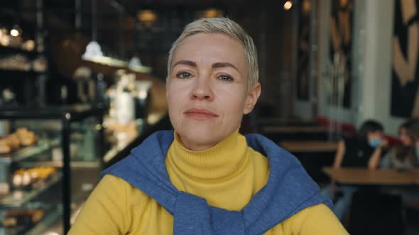 Middle Aged Woman Looking at Camera with Calm Face at Cafe