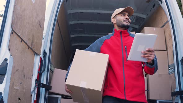 Young Indian Man Courier Using Tablet While Delivering Parcel