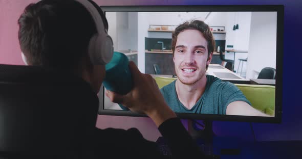 Rear View of a Young Man with Headphones Watching a Video Blog Indoors