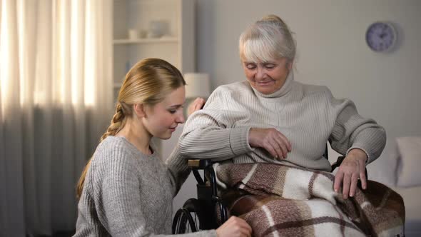 Granddaughter Gently Covering Handicapped Grandmother With Blanket, Support