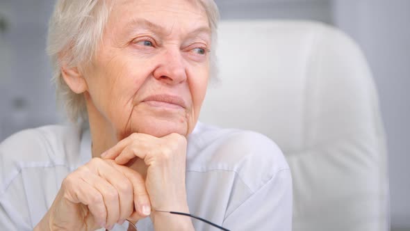 Thoughtful wise aged lady with sad eyes wrinkly face