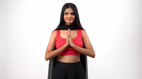 A beautiful and attractive Indian girl in an Indian ethnic outfit doing Namaste by joining hands