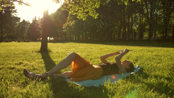 Girl Lying in the Park on Chest and Use the Internet on Tablet PC.