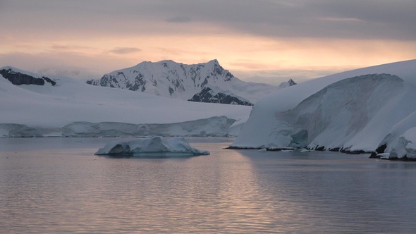 Arctic. Sunset, glaciers and icebergs. Landscape of snowy mountains and icy shores in Antarctica.