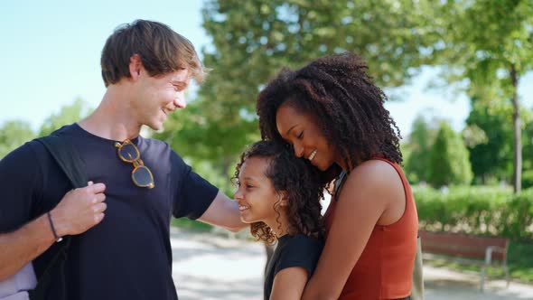 Lovely multiethnic family hugging and talking in the park