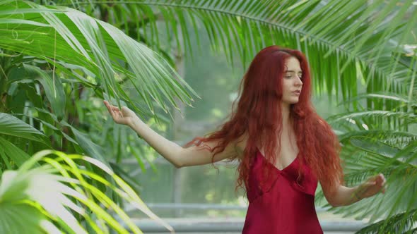 Redhead woman surrounded by palm tree leaves