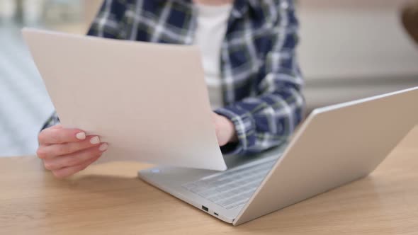 Female Reading Documents While Using Laptop Close Up