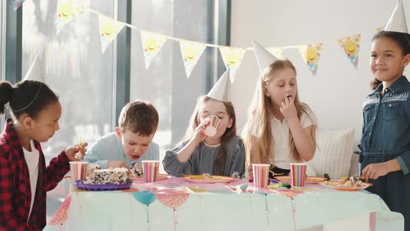 Group of Children Eating at Birthday Party in Funny Decorations