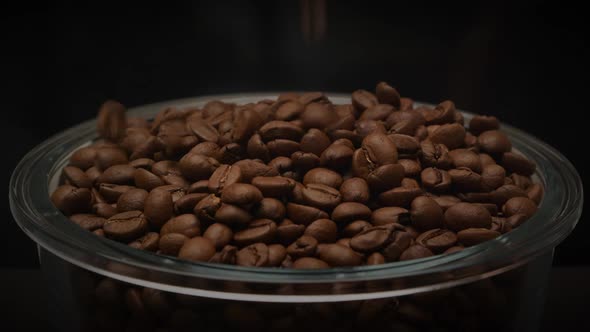 Aromatic Roasted Coffee Beans Falling Into Glass Plate on Dark Background in Slow Motion