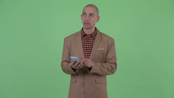 Serious Bald Multi Ethnic Businessman Thinking While Using Phone