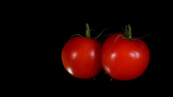 Two Ripe Tomatoes are Flying Towards Each Other Colliding on Black Background