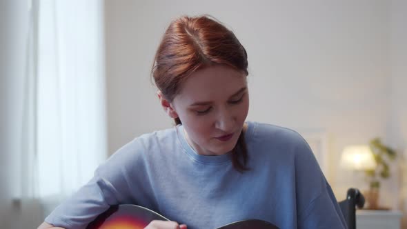 A Young Disabled Lady is Playing the Guitar and Singing Songs