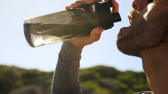 Triathlete man drinking water on a sunny day