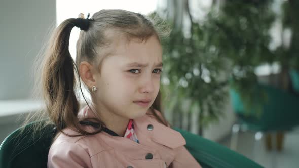 Upset Little Girl Crying in a Cafe By the Window