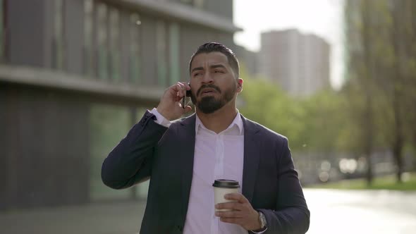 Man Talking By Smartphone and Drinking From Paper Cup Outdoor