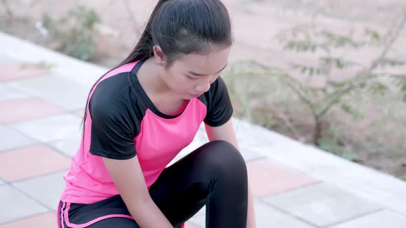 Young Asian woman tightening sport shoes and running outdoor exercise in pink sportswear