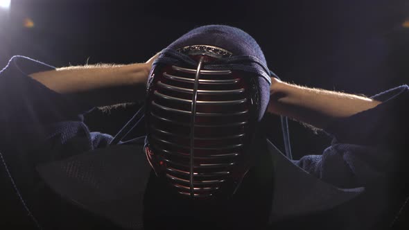 Kendo Warrior Is Putting on Helmet and Lacing It. Close-up