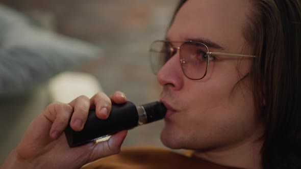 Stylish Young Man with Spectacles Breathes Out White Smoke