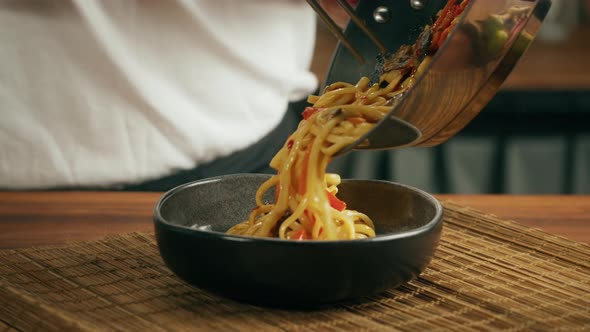 Chef Cooking Asian Rice Noodles with Fried Meat and Spicy Vegetables in Wok Pan