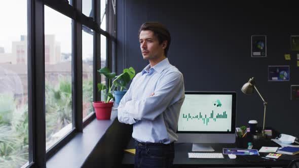 Caucasian businessman standing looking out of window in modern office