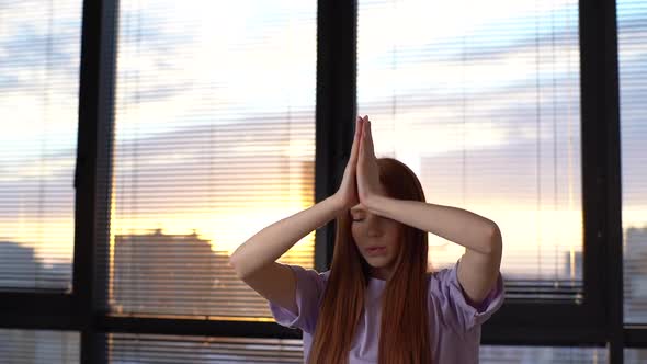 Portrait of Peaceful Redhead Young Woman Does Yoga Asana Raising Hands in Namaste Mudra While