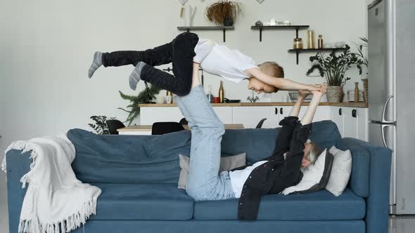 Happy mother lifting little child up fly enjoying family leisure airplane game relaxing on couch