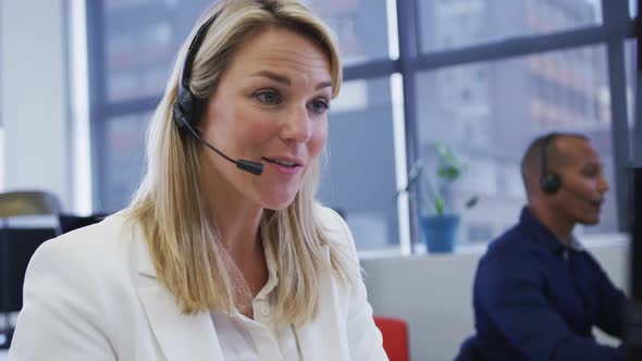 Diverse business people sitting using computers talking with phone headsets