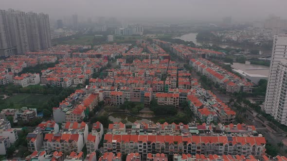 Foggy,smoggy early morning drone footage over urban high-rise and villa housing developments in dist