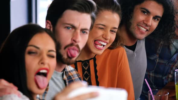 Friends making funny faces and taking a selfie on mobile phone