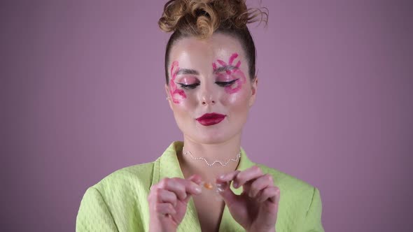 Young Beautiful Woman Professional Make Up Artist with Lipstick Marks Smile at Pink Background