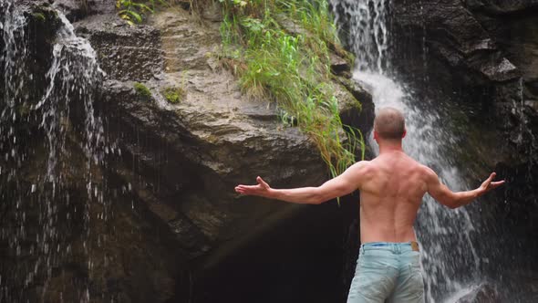 Shirtless Man Happy of Bonding with Nature Near Waterfall