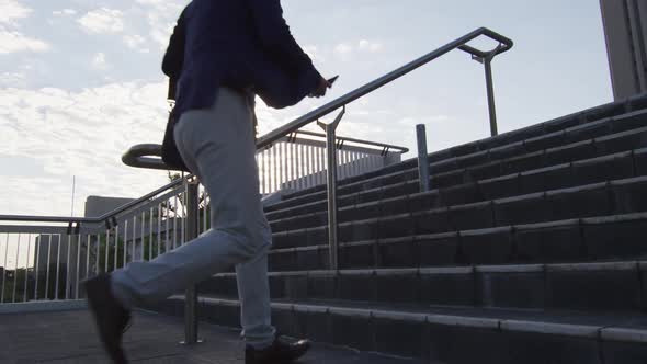 Asian man holding smartphone running while climbing up the stairs at corporate park