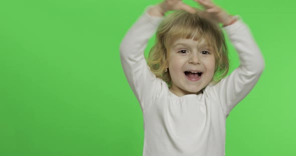 Happy Little Blonde Girl in White T-shirt. Cute Blonde Child. Clapping in Hands