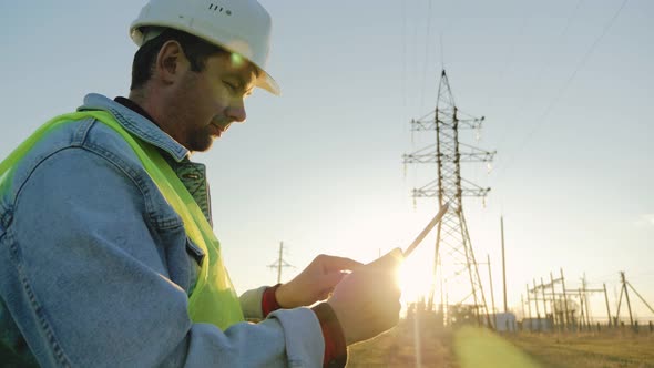 Engineer Standing on Field with Electricity Towers