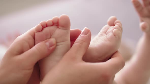 Mother Massaging and Tickling Small Baby Feet. Close Up Slow Motion Shot