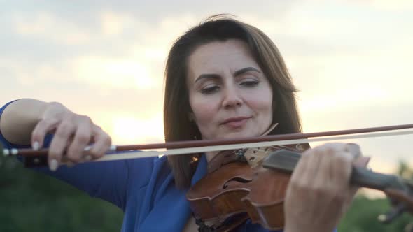 Woman Playing Violin at Sunset