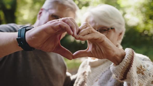 Older Retired Couple Making Heart with Their Hands. Selective Focus