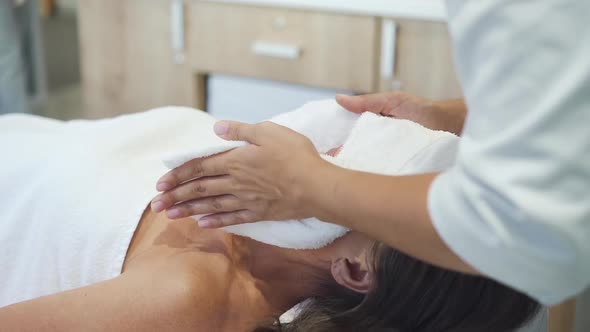 Cosmetology Doctor Putting Towel To Face of Adult Female Customer