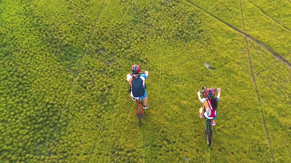 Footage B Roll 4k. Aerial view Drone tracking young People riding a bikes on the meadow