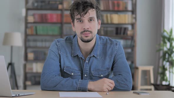 Portrait of Serious Young Man Looking at Camera in Casual Office