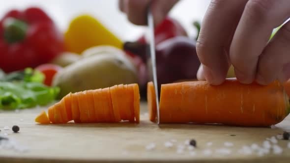 Male Hands Cutting Carrot on Wooden Board