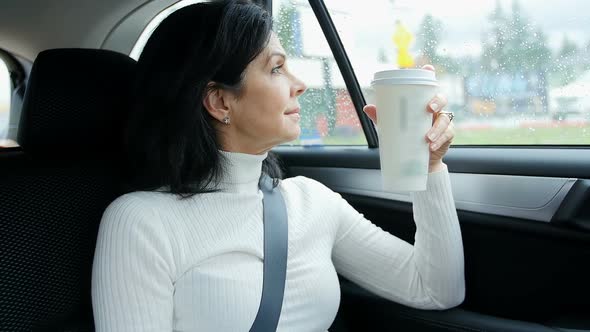 Woman sitting in car holding disposable cup