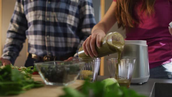 Senior caucasian father and teenage daughter preparing health drink in kitchen