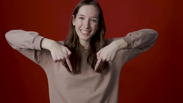 A Positive Young Woman Points Her Fingers Down Indicating a Spot for your Advertisement