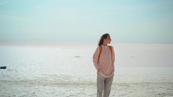 Cheerfulness Woman in Cozy Sweater with Orange Backpack on Nature Landscape of the Salt Flats Looks