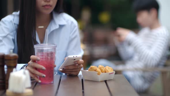 Woman Typing on Smartphone and Drinking Soda at Lunch